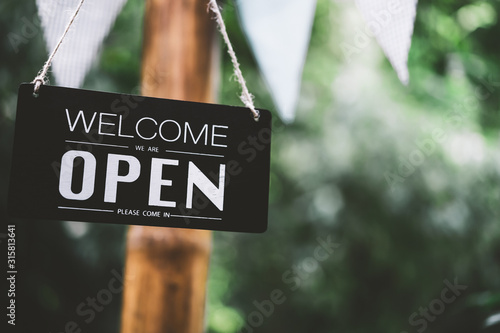 Fotografía Open sign hanging on tree with green nature bokeh sunlight background