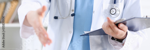 Cuadros en Lienzo Female medicine doctor hold pad and give arm to shake in office closeup