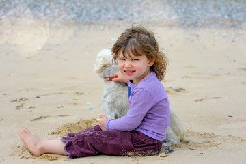 cute little girl playing with her dog on the beach