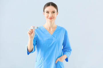 Wall Mural - Portrait of female doctor with thermometer on light background