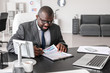 © Pixel-Shot - Handsome African-American businessman working in modern office