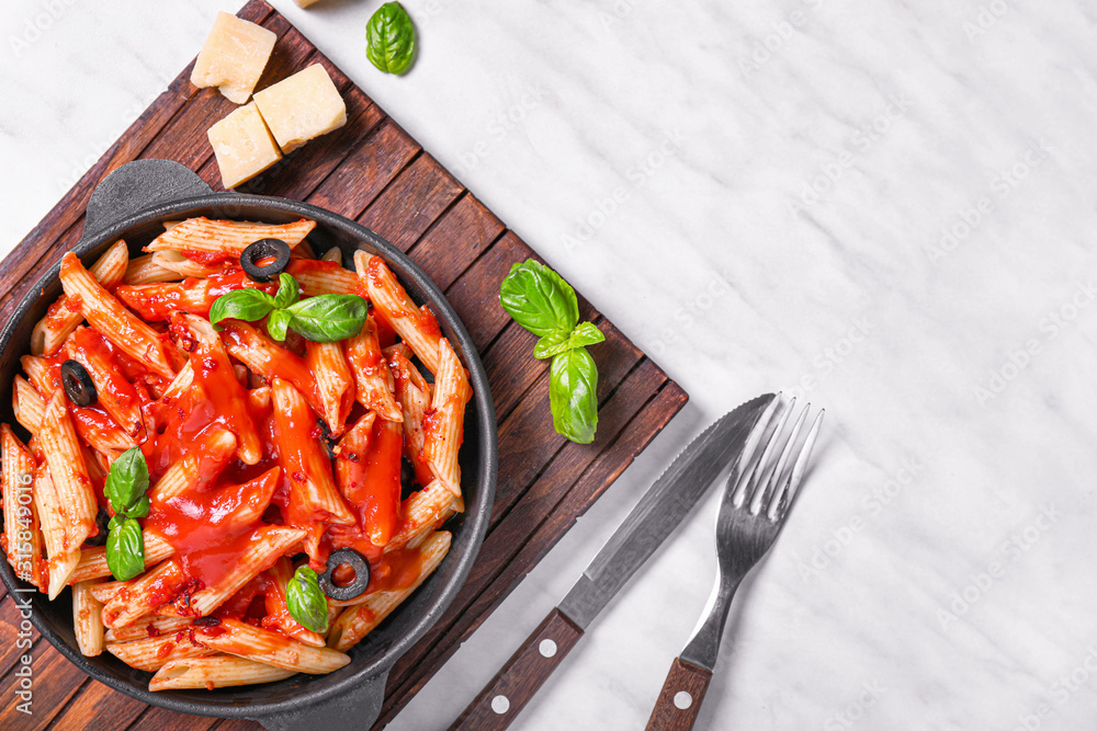 Frying pan with tasty pasta and tomato sauce on white table
