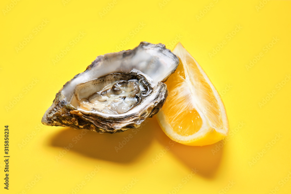 Tasty oyster with lemon on color background