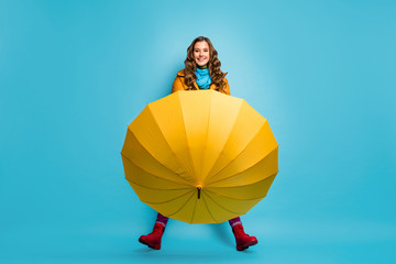 I don't need it. Full length photo of pretty lady hold umbrella enjoy spring sunny day street wear yellow overcoat blue scarf trousers red boots isolated blue color background