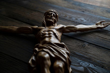  Cruciefied Jesus Figure Isolated On Rustic Dark Brown Table.
