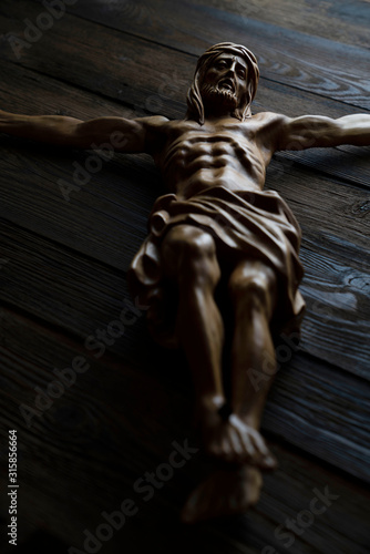 Fotomural Cruciefied Jesus figure isolated on rustic dark brown table.