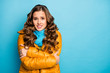 Photo of pretty curly traveler lady upset frosty winter day shaking all body walk street hug herself wear trendy casual yellow overcoat blue scarf isolated blue color background