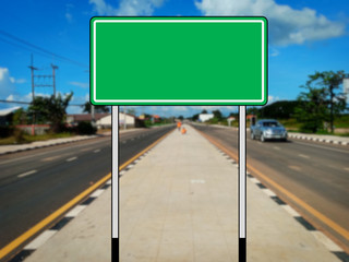 Wall Mural - Green blank traffic sign without message The background of the road is blurred