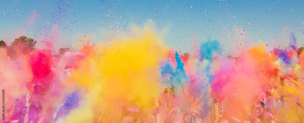 Crowd throwing bright colored powder paint in the air at Holi Festival Dahan - obrazy, fototapety, plakaty 