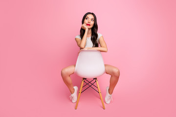 Portrait of her she nice-looking attractive charming lovely cheerful dreamy wavy-haired girl sitting on chair thinking about holiday vacation isolated over pink pastel color background