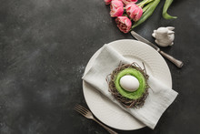 Easter Table Setting With White Egg In Nest And Tulip On Dark. Top View.