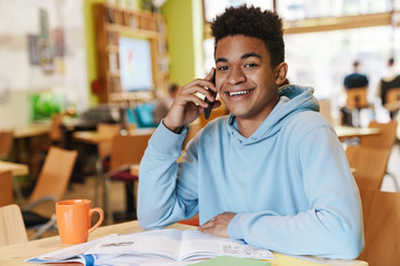 Poster - Smiling african bot teenager studying while sitting at the hub