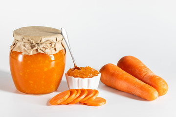 Wall Mural - Delicious homemade carrot jam with lemon in a glass jar on a white background.