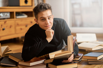 Young handsome student learns on the floor with books for exam 