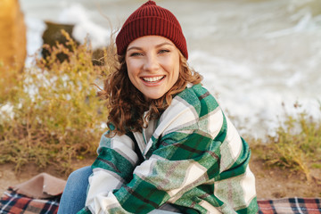 Image of caucasian woman smiling and looking at camera while sitting