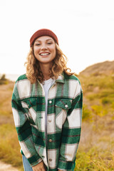 Sticker - Image of young woman wearing hat and plaid shirt walking outdoors