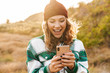 © Drobot Dean - Image of joyful young woman holding cellphone while walking outdoors