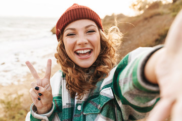 Image of caucasian woman taking selfie photo while walking outdoors