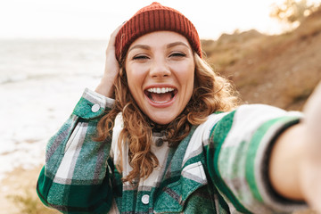 Image of caucasian woman taking selfie photo while walking outdoors