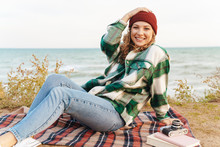 Image Of Joyful Young Caucasian Woman Sitting On Blanket By Seaside