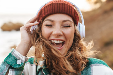 Canvas Print - Image of woman listening to music with headphones while walking outdoors