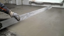 The Process Of Leveling Floors In The Apartment With A Solution. Construction Work, Concrete Cement Plaster. Using A Spatula, Level Or Level The Concrete Slab During The Construction Phase.