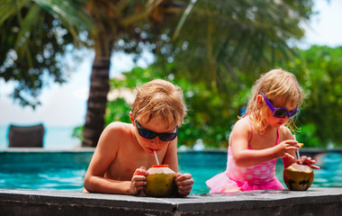 little boy and girl drinking coconut cocktail on beach resort