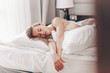 Portrait of a beautiful attractive sleepy woman enjoying a weekend morning in a comfortable bed. Cute caucasian girl is relaxing in a hotel. Holidays weekend and relaxation concept
