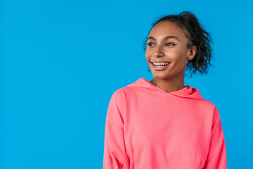 Attractive young african woman with afro hairstyle smiling over blue background