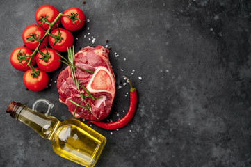 Raw beef steak with tomatoes and spices on a concrete background with copy space for your text. 