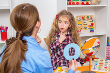 Young Girl  In Speech Therapy Office. Preschooler Exercising Correct Pronunciation With Speech Therapist.