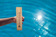© Aleksej - Woman holding thermometer on the pool background. Hot weather and summer concept