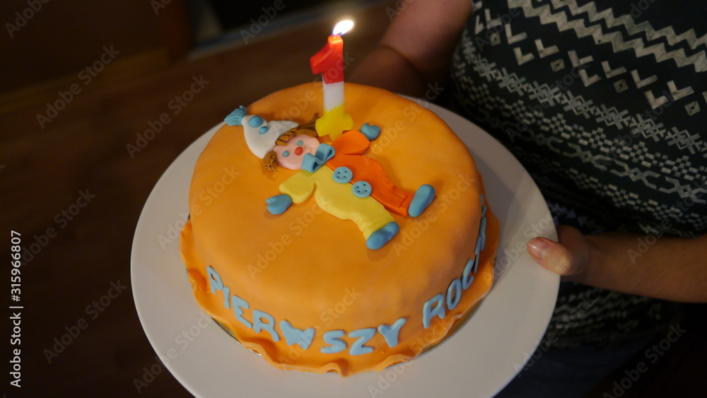 Tort urodzinowy z napisem w języku polskim pierwsze urodziny i świeczką jeden roczek - obrazy, fototapety, plakaty 