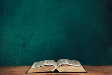 Aufkleber - Open bible on a red old wooden table. Beautiful green wall background.