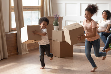 Wall Mural - Overjoyed black kids running, playing with carton boxes.