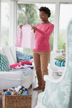 Mid Adult Woman Folding Laundry In Sunroom