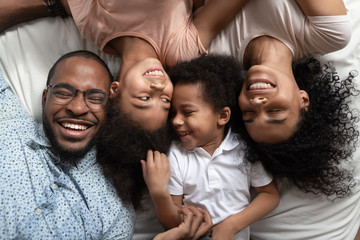 Wall Mural - Smiling black family relaxing on bed with closed eyes.