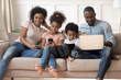 © fizkes - Happy black family addicted to internet technology.