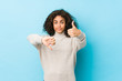 Young african american curly hair woman showing thumbs up and thumbs down, difficult choose concept