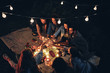 © HBS - Happy friends having fun with fire sparkles. Young people millennials camping at picnic after sunset