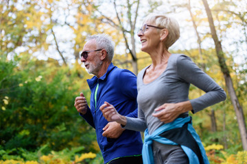 Cheerful active senior couple jogging in the park. Exercise together to stop aging.