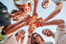 Down View Image Of A Group Of Happy Friends Clinking Beer Bottles Standing Together