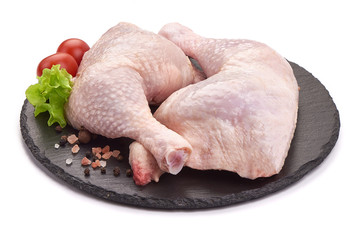 Raw chicken leg quarters on a stone plate, isolated on white background