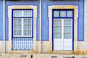 Colorful wooden doors and windows in the facade of a typical Portuguese house - facade covered with azulejos tiles