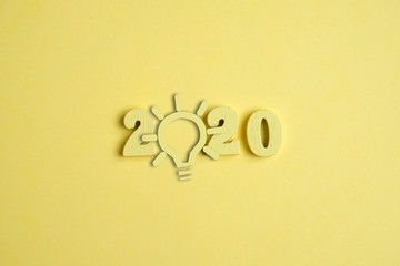 Creative idea concept in the new year 2020. A yellow light bulb next to the numbers on the yellow background.