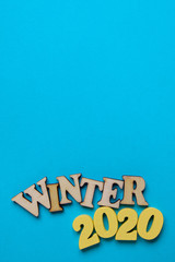 The concept of winter in the new year. Wooden numbers 2020 with letters on a blue background. Top view. Vertical.