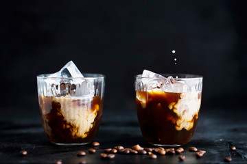 Pouring milk into a glass of espresso coffee with ice