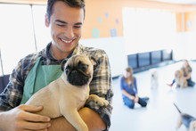 Smiling Man Holding Pug At Dog Daycare