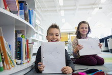 Portrait Of Elementary Students Showing Drawings In Library