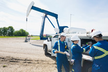 Workers Using Equipment On Truck Near Oil Well